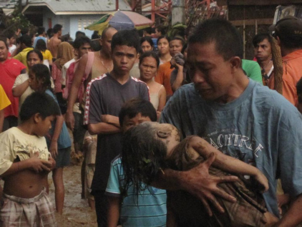 In Cagayan de Oro, an unidentified father breaks down after recovering the body of his child, who was among hundreds killed by Storm Sendong.