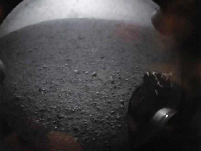 A shot from a NASA video screen shows one of the first images from the Curiosity rover (with one of its wheels shown) after it successfully landed on Mars on Monday. 